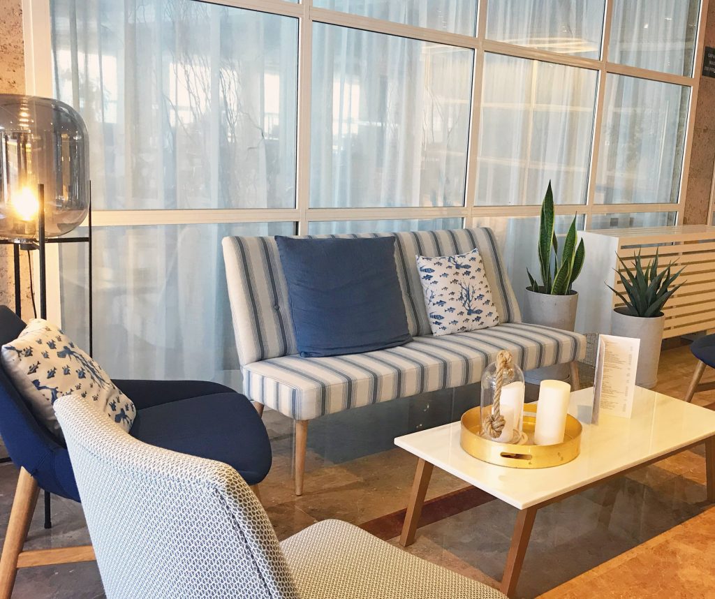 Zona lounge del Hotel Sóller diseñada por Kika Sagristà con sofá azul, madera natural y estilo mediterráneo