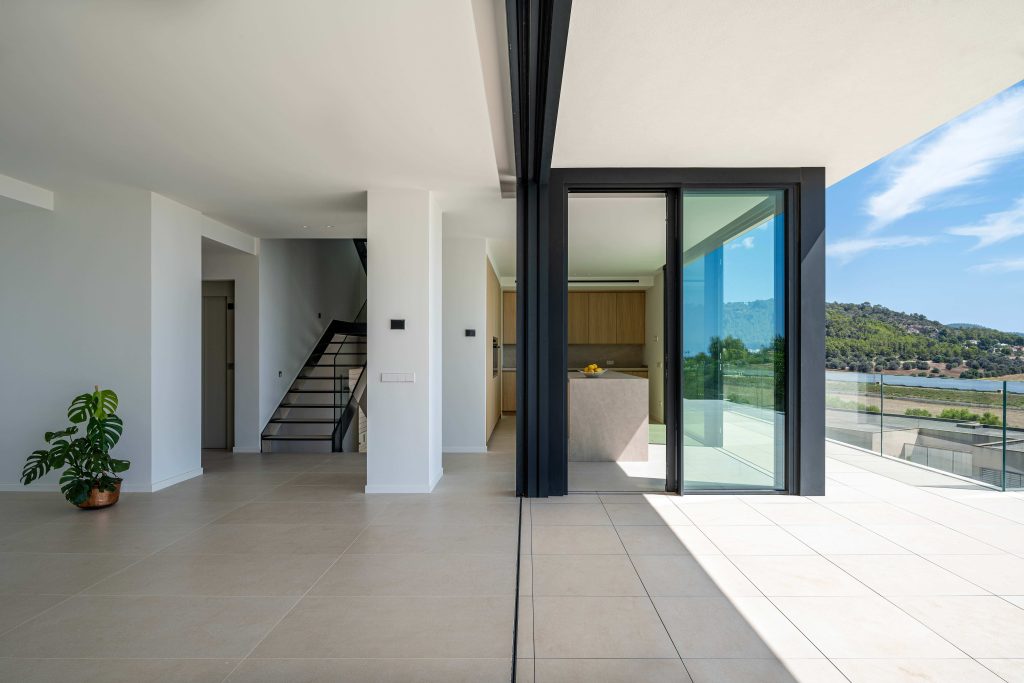 Interior de vivienda contemporánea con grandes puertas correderas de vidrio y conexión a terraza en Mallorca